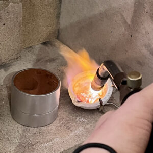 Melting silver in a crucible with a hot gas torch flame.